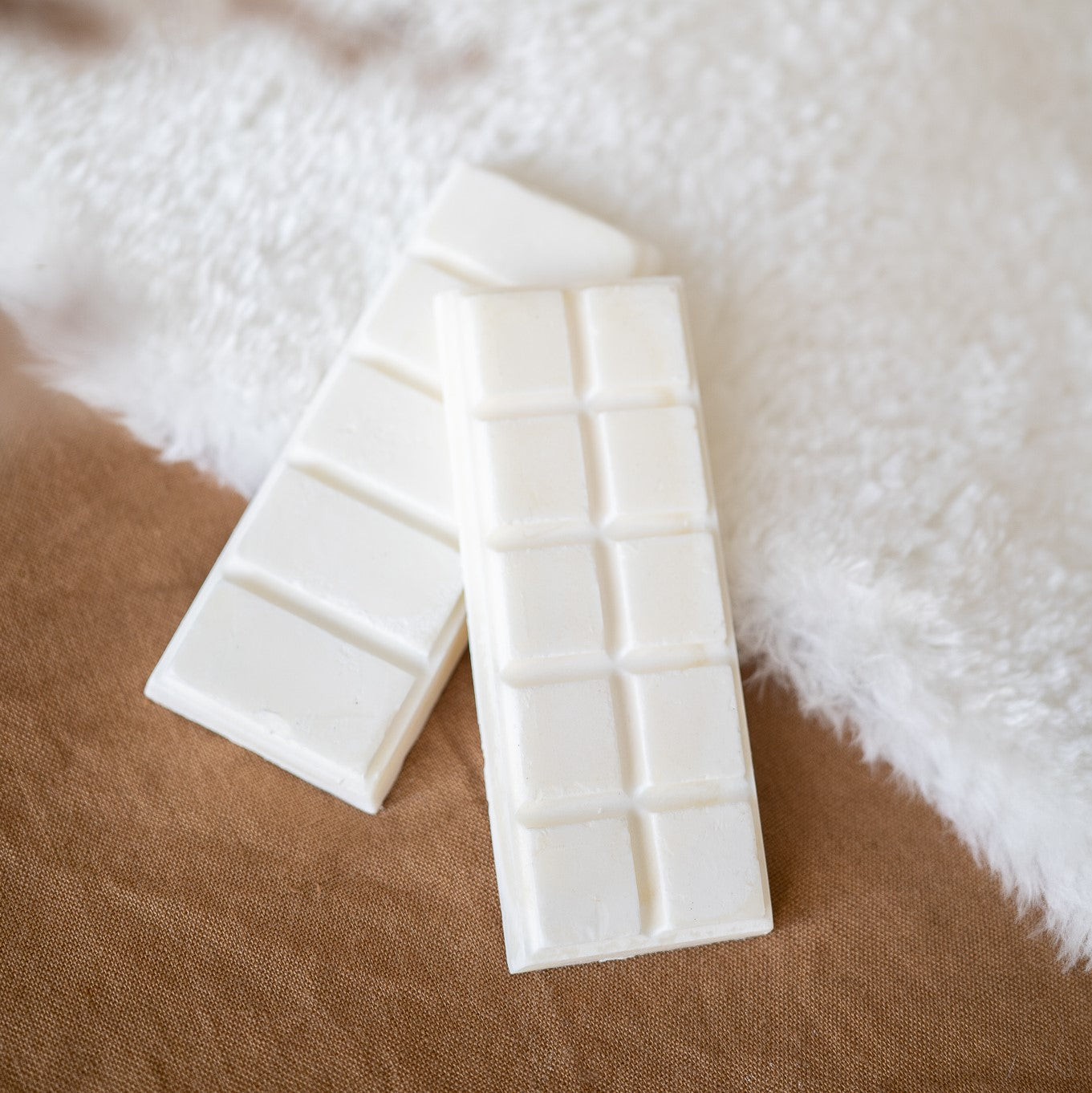 Two break-away wax melts laying on a rug. Made by Paige Soy Candles